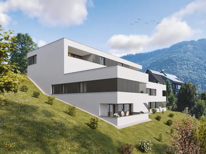 Modernes, weisses Mehrfamilienhaus mit grossen Fenstern und Balkonen am Hang in Feldkirch, umgeben von grünen Wiesen und Bergen (Rauhenweg).