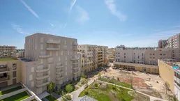 Weitläufige Ansicht eines modernen Wohnkomplexes mit mehreren Gebäuden und einer zentralen Grünfläche.