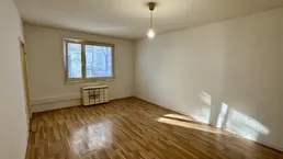 Helles Zimmer mit Parkettboden und weiß gestrichenen Wänden, ideal als Wohn- oder Schlafzimmer.