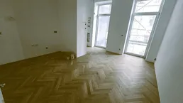 Heller Raum mit Fischgrätparkett und großen, schrägen Fenstern, bereit für den Innenausbau.