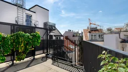 Geräumige Dachterrasse mit Blick auf die umliegenden Gebäude und den Himmel.