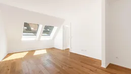 Lichtdurchfluteter Wohnraum im Dachgeschoss mit Holzboden und schrägen Wänden, ideal für individuelle Gestaltung.