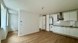 Heller offener Wohnbereich mit integrierter Küche und modernem Laminatboden.