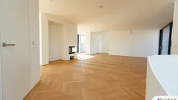 Heller, geräumiger Wohnbereich mit elegantem Fischgrätparkett und integriertem Kamin.