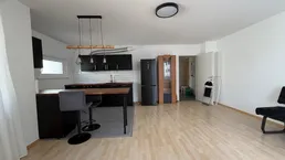 Offener Wohnbereich mit integrierter Küche, Holzboden und viel Tageslicht.
