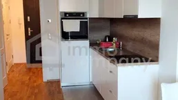 Moderne Küchenzeile integriert in einen hellen Wohnbereich mit Holzboden und weißen Schränken.