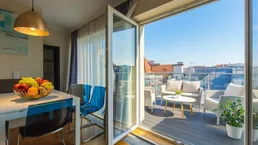 Heller Essbereich mit modernem Tisch und Stühlen, direktem Zugang zur Dachterrasse und Stadtblick.