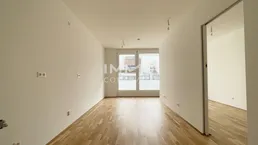 Helles, leeres Zimmer mit Parkettboden und Zugang zu einem Balkon, bereit zur individuellen Gestaltung.