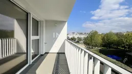 Moderner Balkon mit Fliesenboden und Blick auf grüne Bäume und Gebäude.