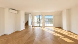 Helles, geräumiges Wohnzimmer mit Fischgrätparkett, Klimaanlage und Zugang zu einem Balkon mit Weitblick.