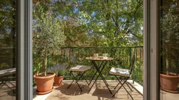 Gemütlicher Balkon mit Sitzgelegenheiten und üppigem Grünblick, ideal zum Entspannen.