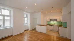 Helle, offene Wohnküche mit Holzboden, moderner Einbauküche und viel Tageslicht.