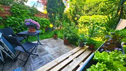 Gemütliche Terrasse mit Holzbodenfliesen, Gartenmöbeln und einem Hochbeet für frisches Gemüse.