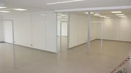 Helles, modernes Büro mit Glaswänden und Fliesenboden, ideal für flexible Arbeitsplatzgestaltung in einem Neubau.