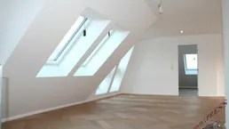 Helles Dachgeschosszimmer mit schrägem Dach, Dachfenstern und Fischgrätparkettboden.