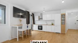 Moderne offene Küche mit weißen Schränken, Holzboden und integriertem Essbereich.