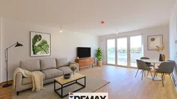 Helles, modern eingerichtetes Wohn-Esszimmer mit Holzboden und Zugang zu einem Balkon.