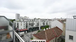 Blick über die Straße auf umliegende Gebäude und einen Supermarkt unter bewölktem Himmel.