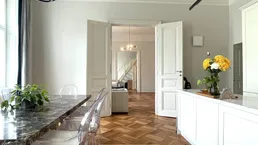 Heller Essbereich mit Marmortisch und Blick in das angrenzende Wohnzimmer mit Parkettboden.
