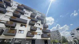 Moderne Wohnanlage mit vielen Balkonen unter blauem Himmel an einem sonnigen Tag.