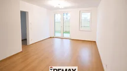 Helles, unmöbliertes Zimmer mit Holzboden und Zugang zu einem kleinen Gartenbereich oder einer Terrasse.