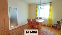 Gemütlicher Essbereich mit Holztisch, Stühlen und einem großen Holzschrank, beleuchtet durch ein Fenster.