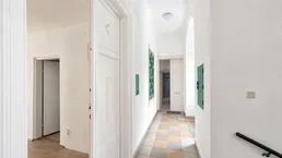 Heller Flur mit karierten Fliesen und weißen Wänden, der zu weiteren Räumen führt.