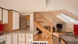 Offener Wohn- und Essbereich mit integrierter Küche, Holztreppe und Dachschrägenfenstern für viel Licht.
