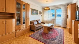 Gemütliches Wohnzimmer mit traditionellen Holzmöbeln, bequemer Couch und Blick nach draußen.