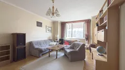 Gemütliches Wohnzimmer mit Fischgrätparkett, großem Sofa und Bücherregal, das viel Stauraum bietet.