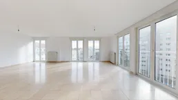 Heller, leerer Wohn- und Essbereich mit Fliesenboden und mehreren großen Fenstern.