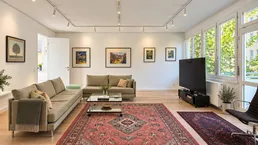 Helles Wohnzimmer mit Holzboden, großen Fenstern und gemütlichen Sofas, ideal zum Entspannen.