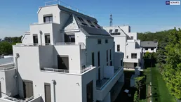 Moderne weiße Wohngebäude mit gestuften Balkonen und Solarpaneelen auf den Dächern, umgeben von Grünflächen.