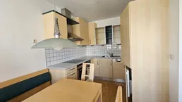 Helle Küche mit Holzelementen, integrierter Essecke und funktionaler Ausstattung.
