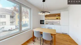 Moderner Essbereich mit Holztisch und Stühlen, angrenzend an eine helle Küche mit großen Fenstern.