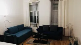 Gemütliches Wohnzimmer mit zwei Sofas, Holzboden und hellen Wänden, ideal zum Entspannen.