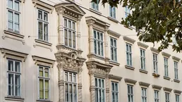 Detailansicht einer historischen Fassade mit reich verzierten Fenstern und Stuckelementen.