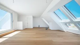 Helles Dachgeschosszimmer mit Holzboden, großen Fenstern und Zugang zu einem Balkon.