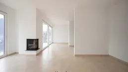 Heller, leerer Wohnraum mit modernen Fliesen, großen Fenstern und integriertem Kamin.