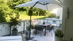 Geräumiger Balkon mit Fliesenboden, bequemen Gartenmöbeln und Blick ins Grüne.