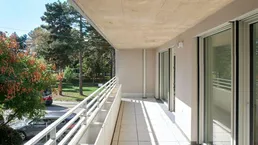 Langer, sonniger Balkon mit Fliesenboden und Blick ins Grüne, ideal zum Entspannen.
