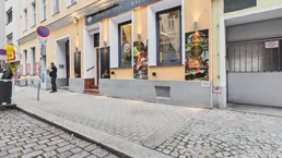Außenansicht eines Gebäudes mit einem Restaurant im Erdgeschoss und Kopfsteinpflaster auf der Straße.