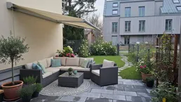 Gemütliche Terrasse mit bequemen Gartenmöbeln, Markise und Blick auf den gepflegten Garten.