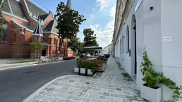 Blick auf eine belebte Straße mit einer Kirche, einem Gebäude und einer Außenterrasse mit Sitzgelegenheiten.