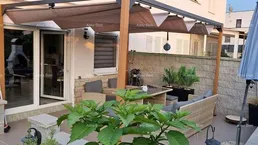 Gemütliche Außenterrasse mit Pergola, Sitzgelegenheiten und Sonnenschirm für entspannte Stunden im Freien.