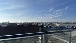 Weitläufiger Blick über die Stadt von einer Dachterrasse unter blauem Himmel.