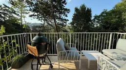 Geräumige Terrasse mit Grillbereich und bequemen Sitzgelegenheiten, umgeben von viel Grün.