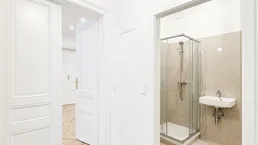 Heller Flur mit Fliesenboden, der zu einem Badezimmer und weiteren Räumen führt.