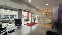 Heller Empfangsbereich mit großen Fenstern zur Straße, modernen Sitzgelegenheiten und einer stilvollen Theke.