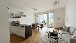Heller offener Wohn- und Essbereich mit Parkettboden, Balkonzugang und moderner Einrichtung.